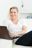 Woman using a laptop while sitting on a sofa