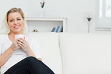 Woman on a sofa drinking a coffee