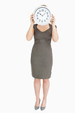 Woman holding a clock hiding her head
