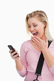 Surprised blonde woman looking at her mobile phone