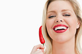 Blonde woman holding a chili while laughing