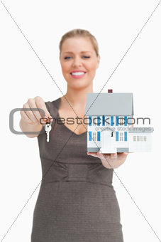 Woman showing a key and a model house
