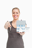 Woman smiling showing a model house and a key