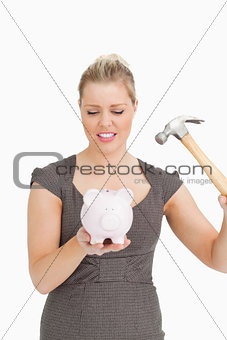 Serious woman with a piggy bank and a hammer