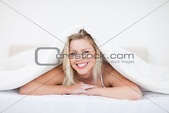 Young blonde woman lying under a duvet