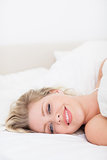 Smiling woman lying under a white duvet