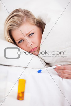 Sick young woman holding a thermometer