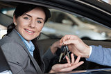 Smiling woman in a car receiving car keys