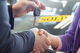 Person shaking hands in front of a sold car 