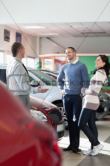 Smiling couple talking with a car dealer