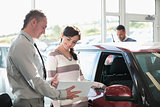 Smiling woman chatting with a car dealer