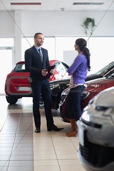 Salesman and a woman talking next to a car
