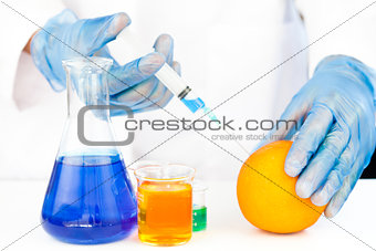 Chemist injecting product in an orange