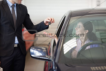 Smiling woman in a car taking keys