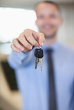 Salesman holding car keys by his fingertips