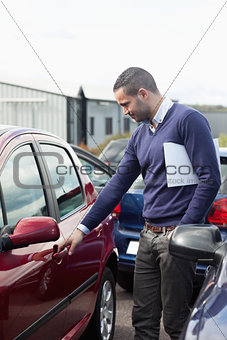 Man looking at a car door while opening it 