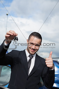 Man holding car keys while raising his thumb