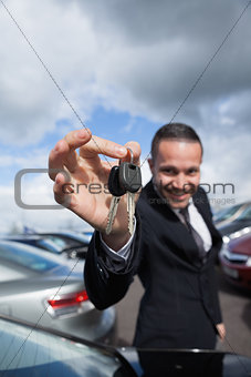 happy dealer holding car keys by his fingertips