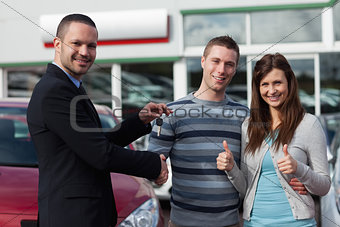 Dealer shaking hand of a man while giving him car keys