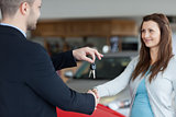 Salesman giving car keys while shaking hand of a woman