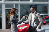 Businesswoman giving car keys to a man