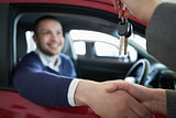 Woman giving car keys while shaking hand