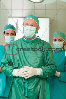 Surgeon joining his hand with interns behind him