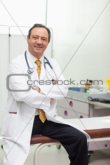 Doctor smiling while sitting on a table