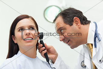 Doctor using an otoscope to look at the ear of his patient