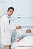 Doctor standing next to his patient while holding a chart