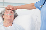 Nurse putting her hand on the forehead of a patient