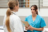 Nurse holding a file and talking to a doctor
