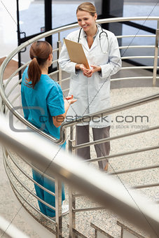 Doctor holding a file while talking to a nurse