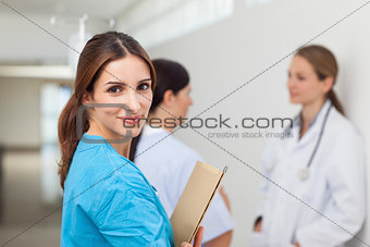 Nurse in a hallway with a doctor and a patient while holding fil