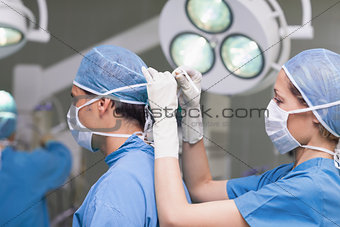 Nurse tying the mask of the doctor