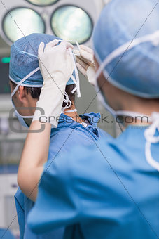 Close up of a nurse tying a mask of a doctor