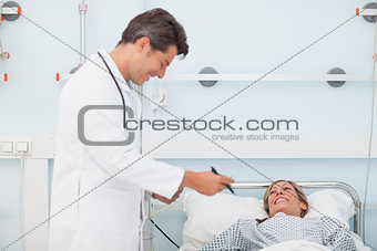 Doctor looking at his chart next to his patient