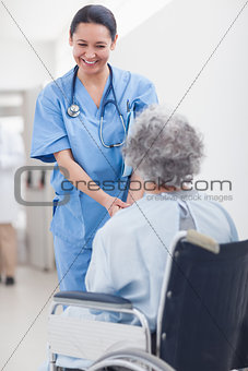 Nurse smiling while holding the hands of a patient