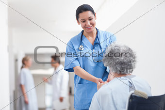 Nurse standing next to a patient while holding her hands