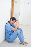 Sad nurse sitting on the floor