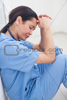 Nurse sitting on the floor with her head on her hands