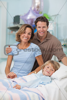 Child lying on a medical bed next to his parents