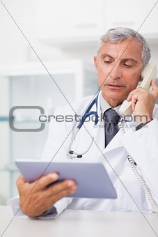 Doctor holding a tablet computer while calling