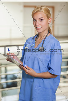 Blonde nurse writing on a clipboard
