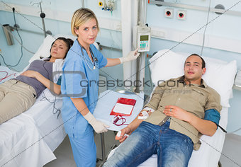 Nurse touching monitor next to transfused patients