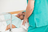 Female patient lying on a bed while looking a doctor