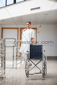 Smiling patient standing next to a wheelchair