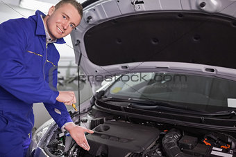 Mechanic showing an engine with his hand