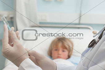 Doctor preparing a syringe in front of a child