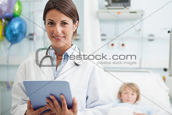 Doctor holding a tablet computer next to a child